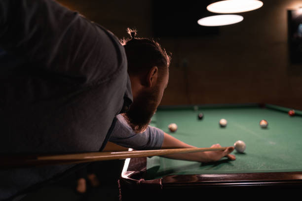 istock A young bearded professional man plays billiards in a dark pool club. 1496187828