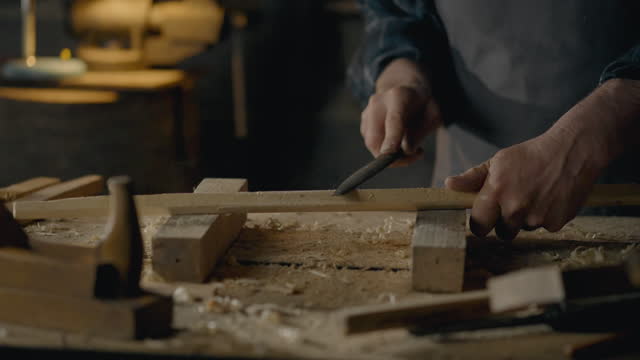 Craftsman, Middle-aged man Concentrated Uses hand tool rasp In a carpentry workshop Close-up Young