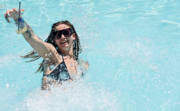 istock Woman falling in pool with drink in hand making splash 1496189406
