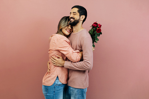 A loving couple celebrates Valentine's Day as the boyfriend gifts his girlfriend a bouquet of roses.