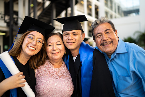 Portrait of young graduates embracing their parents on graduation