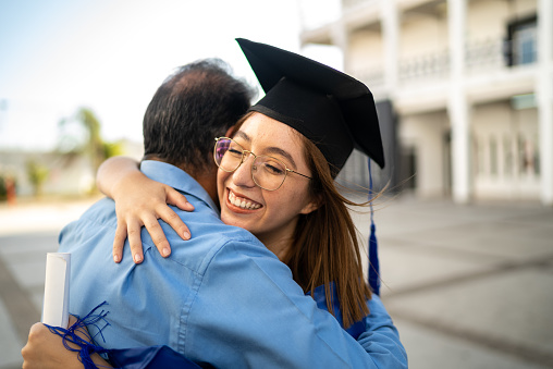 Young graduate woman embracing father on her graduation