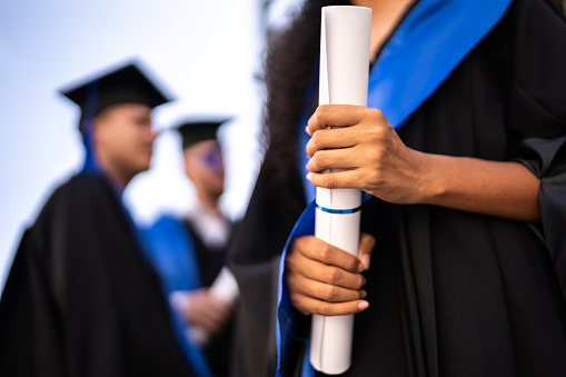 Close-up of a young woman holding a diploma on graduation