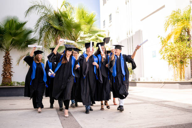 istock Young graduates friends celebrating while walking on graduation 1496191965