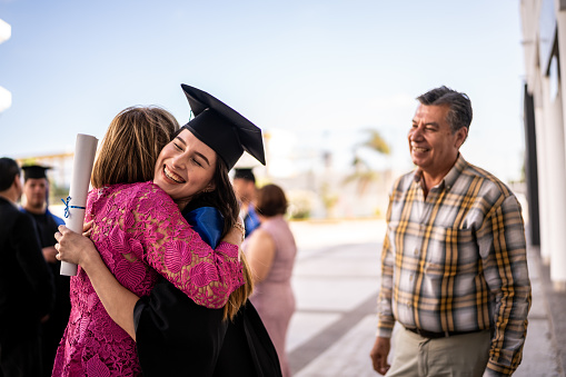 Young graduate woman embracing her mother on the graduation
