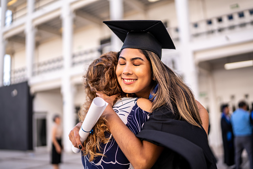 Young graduate woman embracing her mother on graduation