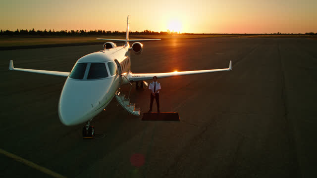 Pilot Standing Next To Private Jet At Sunset