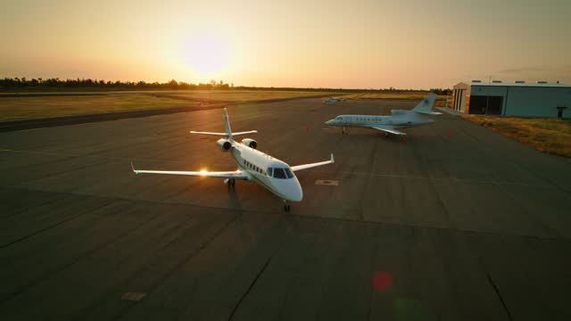 Sun Setting Behind Private Jet Taxiing Away from Runway - Aerial Shot