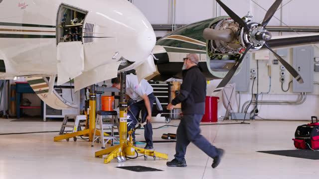 Two Airplane Mechanics Working On Propellor