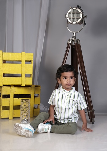 Cute little boy having fun while shoot and making poses, sitting on floor