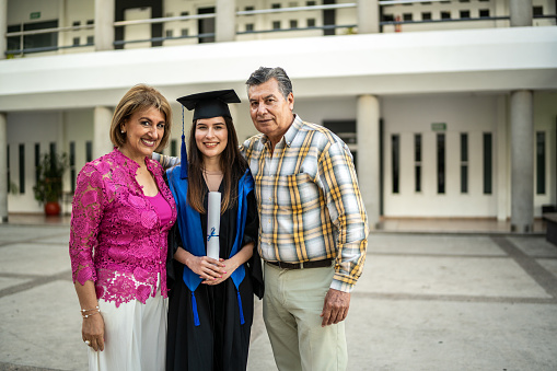 Portrait of young graduate woman with her parents on graduation