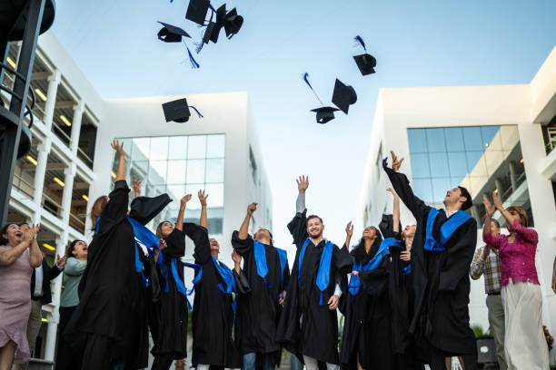istock Young graduates throwing their mortarboard in the air while celebrating on graduation 1496195436
