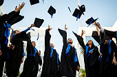 Young graduates throwing their mortarboard in the air while celebrating on graduation