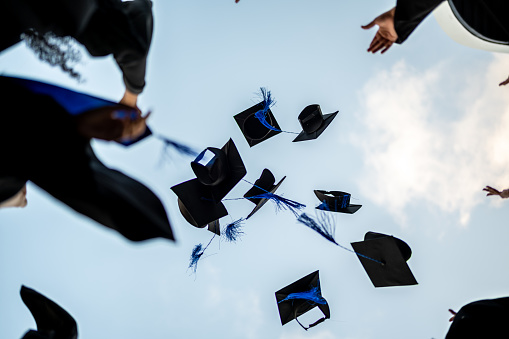 Graduates throwing graduation cap in the air
