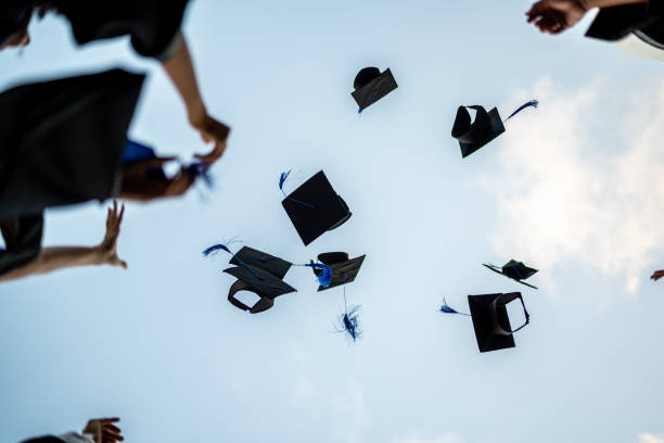 istock Graduates throwing graduation cap in the air 1496195454