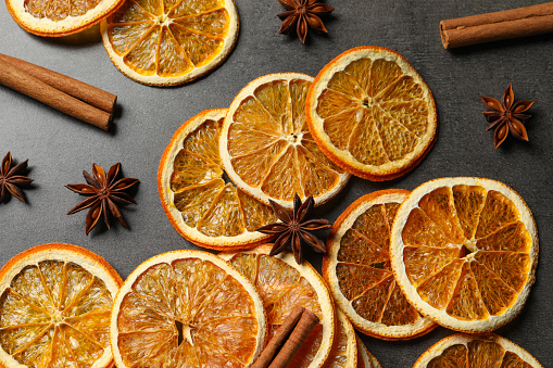 Dry orange slices, cinnamon sticks and anise stars on black table, flat lay