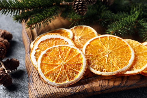 Dry orange slices, cones and fir tree branches on grey table, closeup