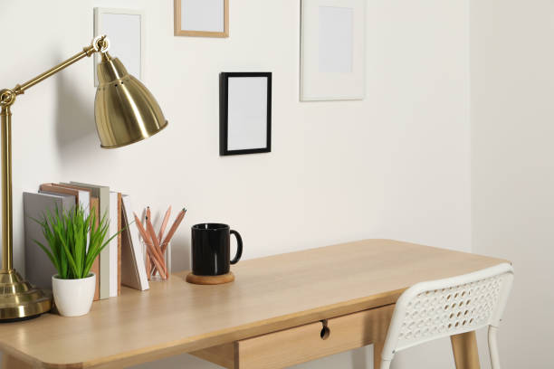 istock Comfortable workplace with wooden desk near white wall indoors 1496197430