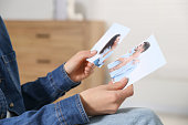 Woman holding torn photo at home, closeup. Divorce concept