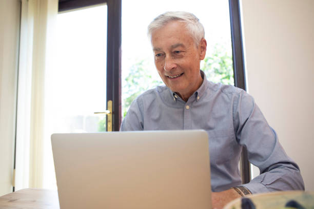 istock Cheerful mature adult using a laptop at home 1496199475