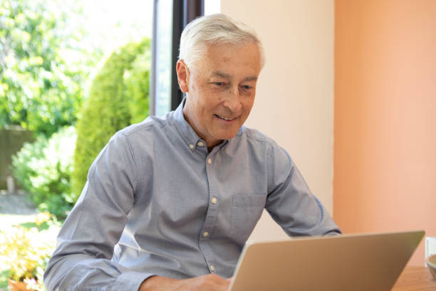istock Cheerful mature adult using a laptop at home 1496199488