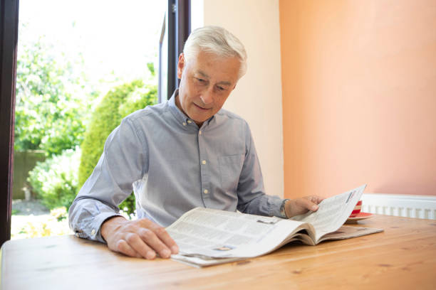 istock Contented mature man reading a newspaper at home 1496199532