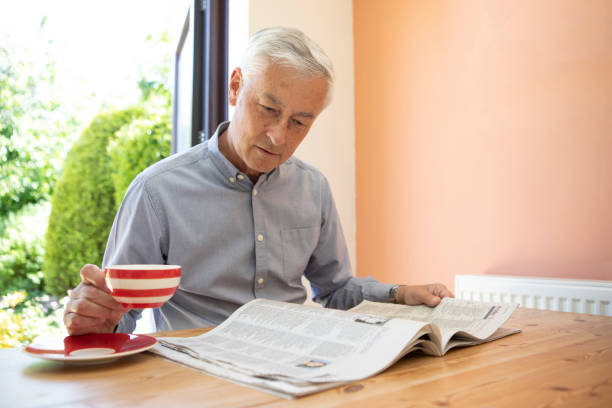 istock Contented mature man reading a newspaper at home 1496199546