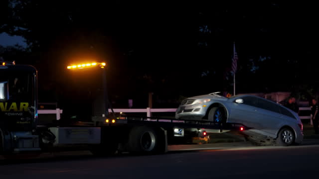 Tow trucks and police at car accident scene on road in night time