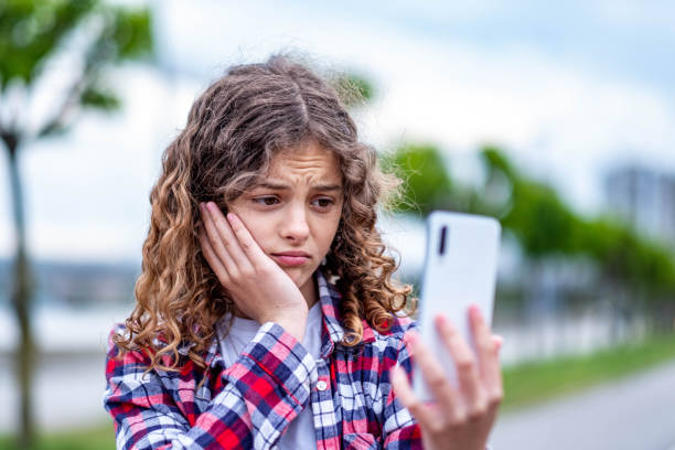 istock little girl sad while looking at the phone 1496209820