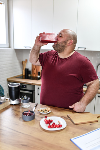 Overweight Male Drinking Smoothie As Part Of Weight Loss Recipe