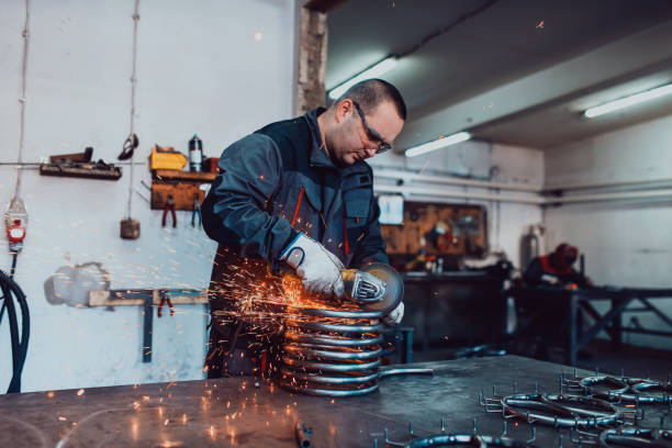istock Locksmith in special clothes and goggles works in production. Metal processing with angle grinder. Sparks in metalworking. 1496215616