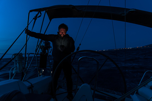 The captain, who is traveling by yacht at night, receives navigation information from his phone.
