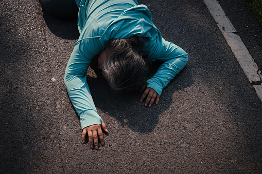 An elderly asian  woman had faints while exercising. lies unconscious on the floor of a park in Thailand