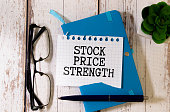 Business concept. On the financial charts lies a pen and a sign with the inscription - STOCK PRICE STRENGTH