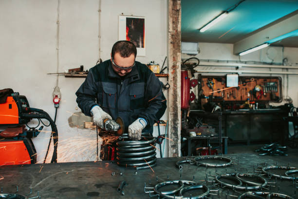 istock Locksmith in special clothes and goggles works in production. Metal processing with angle grinder. Sparks in metalworking. 1496221924