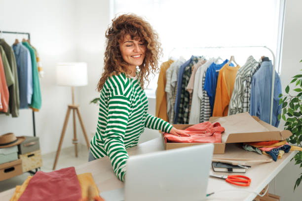 istock Young beautiful woman using laptop at her home based clothing store 1496223921