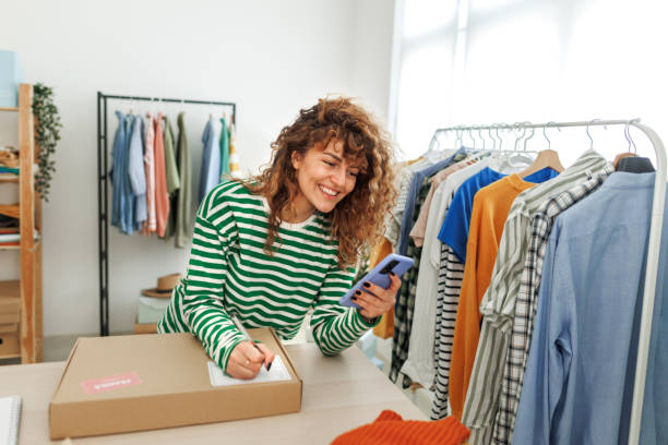 istock Young beautiful smiling woman using smart phone at her home based clothing store 1496223991