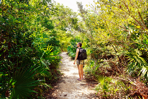 40 year old woman hiking on a lush jungle trail in Quintana Roo, Mexico.
