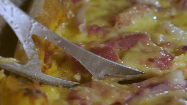 Closer look of the slicer slicing the hot pizza