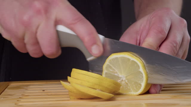 Man cutting a lemon on the chopping board.