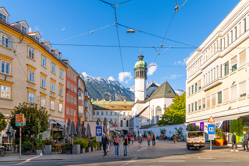 View of the tower and facade of the Innsbruck Hofkirche, a Gothic church located in the Altstadt section of Innsbruck, Austria, with the Austrian Alps in the distance.