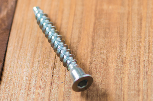 Tapping screw on the wooden table in workshop. Instruments for men's hobby