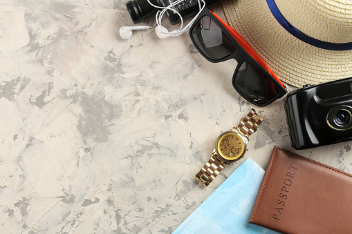 Travel concept hat, passport, map, camera and sunglasses on a light concrete background. top view