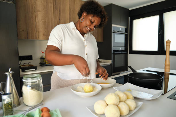 istock Young cuban woman breading mashed potatoes balls. 1496233372