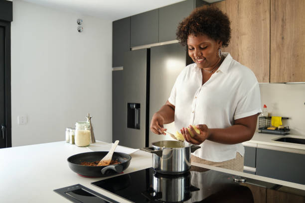 istock Young cuban woman filling mashed potatoes with minced beef. 1496233563