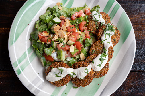 A plate of falafel served with salad of tomatoes, cucumber, greens and almonds.