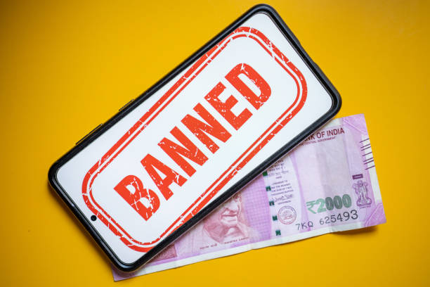 istock Rs 2000 Indian bank note that has been removed from circulation through demonitization on yellow table with mobile showing banned callout 1496246893