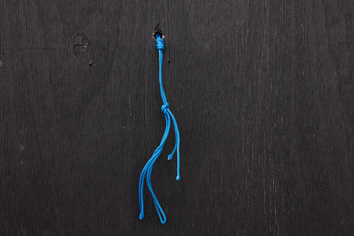 Blue rope tied to a plain black wooden wall