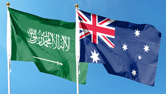 Australia flag and Saudi Arabia flag on cloudy sky. waving in the sky