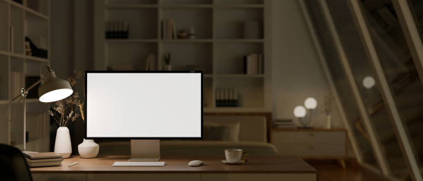 istock Modern cozy home office at night with PC computer mockup on a table. 1496255745